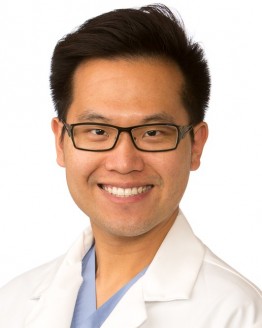 Photo of a doctor in a white coat with black glasses